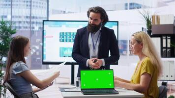 Financial adviser presents market analytics on isolated screen laptop to clients, teaching them how to build portfolio. Broker showing stock exchange charts on chroma key notebook to family, camera B video