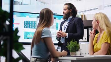 Financial adviser presents market analytics to customers using large display, explore best practices for building portfolio. Broker agent showing stock exchange charts to mother and daughter, camera A video