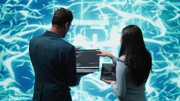 Coworkers doing brainstorming, using devices to fix artificial intelligence neural networks. High tech workspace colleagues using AI system aiding in processing and transmitting information, camera A video