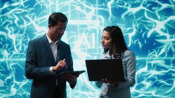 Coworkers solving tasks on laptop and tablet, running artificial intelligence programming scripts. IT staff members using devices to write lines of code for AI applications development, camera A video