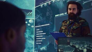 Infantry unit leader coordinating troops to execute special operations, briefing crew with mission details for national safety. Military commander studies real time surveillance data. Camera B. video