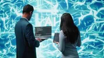 Team of admins using tablet and laptop to maintenance artificial intelligence neural networks. Teamworking IT staff members using AI system aiding in processing and transmitting information, camera A video