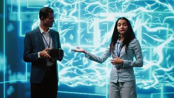 Tech experts presenting VR headset and AI tech during summit presentation, exploring successful implementation of artificial intelligence and virtual reality in driving forward businesses, camera A video
