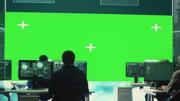 Team of governmental hackers look at green screen in high tech agency office, working together on hacking database systems for cyberwarfare activity. Experts conducting illegal scams. Camera A. video