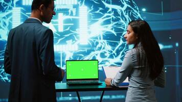 Startup coworkers brainstorming ways to use AI on chroma key notebook to improve data driven decisions. Technicians using mockup laptop to improve artificial intelligence tech, camera A video