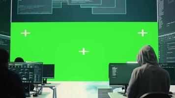 Team of governmental hackers look at green screen in high tech agency office, working together on hacking database systems for cyberwarfare activity. Experts conducting illegal scams. Camera B. video