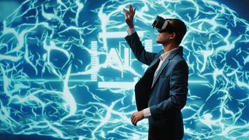 System administrator wearing VR headset looking at hologram of artificial intelligence human brain simulation. IT expert interacting with AI visualization showing deep learning algorithms, camera A video