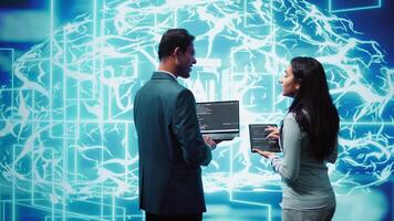 Team of admins using tablet and laptop to maintenance artificial intelligence neural networks. Teamworking IT staff members using AI system aiding in processing and transmitting information, camera B video