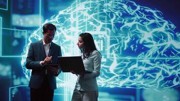 Coworkers solving tasks on laptop and tablet, running artificial intelligence programming scripts. IT staff members using devices to write lines of code for AI applications development, camera B video