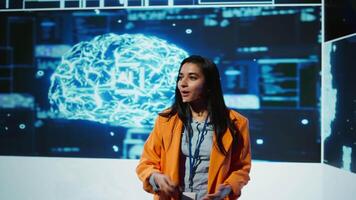 Speaker does EEG headset presentation during tech convention, demonstrating successful implementation of AI in driving forward startup businesses, sharing latest neuroscience discoveries, camera B video