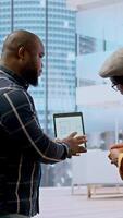 vertical real Estado corretor e cliente negociando uma locação contrato para uma Alto classe moderno escritório espaço, avaliando plantas em tábua durante escritório percorrer. propriedade investimento oportunidade. Câmera uma. video