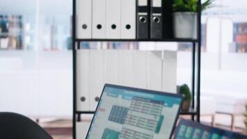 Laptop device on office desk in empty workspace showing volatile stock exchange prices going up and down. Brokerage firm with forex trading platforms indexes on notebook screen video