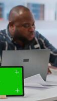 Vertical Clients negotiating with realtor next to isolated copy space on tablet, examining layout and blueprints for new high class office space. Business people investing in property with financier. Camera B. video