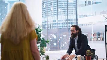 Portrait of cheerful financial advisor in office meeting with parent and child to provide personalized spending planning. Jolly agent in workspace doing handshake with customers, camera A video