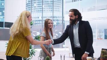 Welcoming financial advisor meeting with clients to recommend financial products and investments, greeting them. Investment strategies expert in workspace doing handshake with customers, camera A video