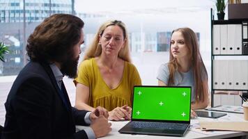 Family receiving personalized financial plan from financial advisor using green screen laptop during meeting. Clients learn how to make profitable decisions from agent using mockup notebook, camera A video