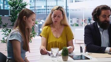 Financial advisor in office with mother and gen Z girl to provide personalized spending plan. Agent evaluating clients financial needs, performing analysis during business meeting, camera A video