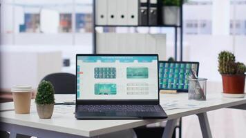 Financial analyst workplace featuring laptop and tablet displaying stock exchange data and statistics. Close up shot of devices on desk next to paperwork with forex trading economic analytics figures video