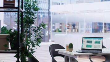 Modern bright office with laptop displaying stock exchange data and statistics. Notebook with forex trading economic analytics figures and documents on desk, cityscape backdrop video