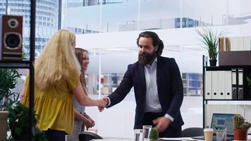 Welcoming financial advisor meeting with clients to recommend financial products and investments, greeting them. Investment strategies expert in workspace doing handshake with customers, camera B video