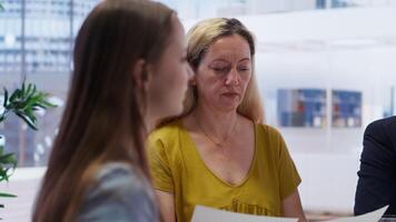 Financial advisor talking with clients, recommending optimal financial services and investments. Agent informing mother and young adult of best investment strategies, camera B video