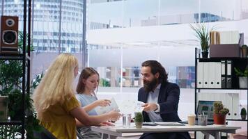 Financial advisor discussing with customers, recommending optimal insurance policies. Agent informing parent and daughter of best investment strategies, offering statistics, camera B video