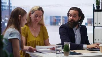 Financial advisor in office with mother and gen Z girl to provide personalized spending plan. Agent evaluating clients financial needs, performing analysis during business meeting, camera B video