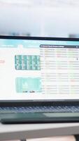 Vertical Empty office with stock portfolio on devices containing collection of investment bonds and other financial assets. Real time index indices showing stock demand surge on laptop and tablet video