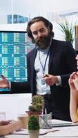 Vertical Broker investor in office offering financial advice to clients, looking at stock exchange volatility on big screen. Financial advisor analyzing market shares growth with mother and daughter, camera A video