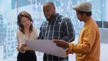 Entrepreneur evaluating an investment opportunity in real estate, reviewing blueprints on tablet and discussing the architectural plans of the new office space with the realtor agent. Camera B. photo