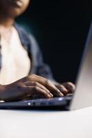 Black woman working on digital laptop, typing and replying emails, browsing online. Detailed view of african american female communicating and utilizing technology as a freelancer. photo