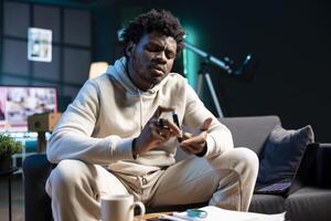 African american man clipping own finger using pulse oximeter, monitoring level of blood oxygen saturation and heart rate during annual checkup from comfort of his dimly lit home photo