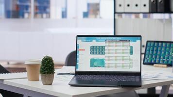 Financial analyst workplace featuring laptop and tablet displaying stock exchange data and statistics. Close up shot of devices on desk next to paperwork with forex trading economic analytics figures photo