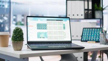 Empty office with stock portfolio on devices containing collection of investment bonds and other financial assets. Real time index indices showing stock demand surge on laptop and tablet photo