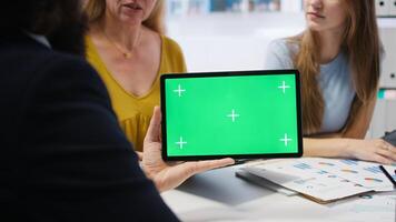 Clients looking over personalized planning guide on isolated screen tablet made by financial advisor. Accountant optimizing living expenses for customers using chroma key device, camera A photo