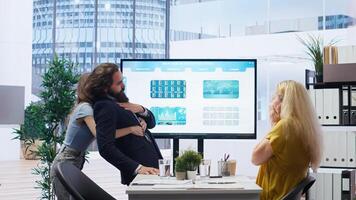 Employee choking in office, being helped by quick thinking coworker performing Heimlich maneuver. Worker offering first aid to colleague while coworker calls for ambulance, camera B photo