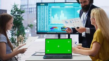 Financial adviser doing presentation on isolated screen laptop to help clients build saving habits, close up. Agent using chroma key notebook to show customers investing tips, camera B photo