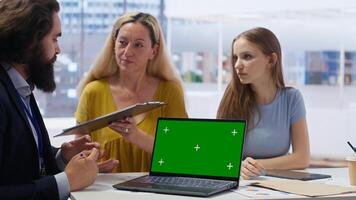 Clients looking over personalized planning guide on green screen laptop written by financial advisor during meeting. Consultant optimizing living expenses for customers using mockup notebook, camera B photo