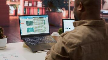 Entrepreneur calculating expenses with online invoices on laptop, creating an analytics reports plan for investment strategy. Working on increasing budget for business expansion. Camera A. photo