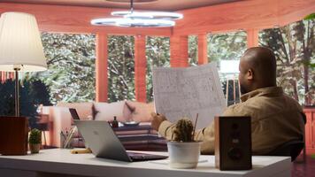 Entrepreneur analyzing architectural sketches and blueprints at his home, planning the layout and design of a new office to foster business development. Hunting for creative workspace. Camera B. photo