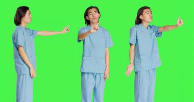 Medical assistant doing no symbol on camera, showing negative reaction and disagreement. Asian healthcare worker being displeased about something, disagreeing and disapproving. photo