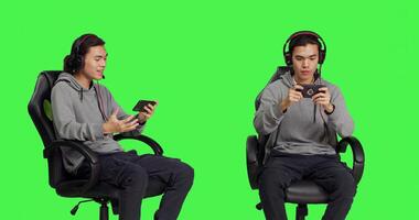 Over greenscreen, asian teenager enjoys mobile games holding smartphone and participating in online multiplayer contest. Gamer uses phone to engage in new roleplaying activity. photo