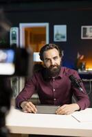 Tech guru doing technology review of wireless portable speaker, filming with professional camera. Influencer showcasing music playing device in living room studio, recording with high quality gear photo