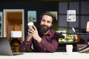 Tech enthusiast in studio presents latest smart light bulb to audience while discussing home improvement in on online channel, highlighting wonders of WiFi home automation photo