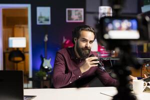 Media star talking into microphone, using professional recording equipment to film vlog channel intro for online streaming platforms. Man greets fans, speaking in mic to present topic of the day photo