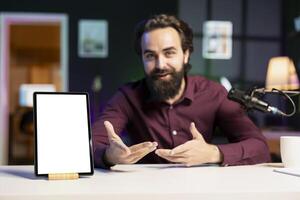 Tech specialist presenting mockup tablet to interested viewers, filming with professional mic. Man reviewing isolated screen digital device, recording with specialized equipment photo