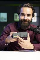 Tech expert filming technology review of newly released V mount battery, presenting features to audience. Reviewer showcasing charging device specs to interested subscribers photo
