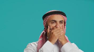 Muslim guy covers eyes, ears and mouth on camera, showing three wise monkeys metaphor symbol. Middle eastern person creating dont hear, see or speak concept sign, islamic attire. photo