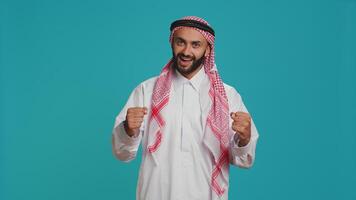 Modern guy cheering and showing his support in front of camera, feeling optimistic and joyful about something. Middle eastern person being brave and giving strength with cheers. photo