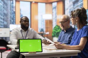 Senior couple meeting with broker expert in modern office, having a green screen on laptop. Financial planner helping old people choose the perfect retirement plan for them. photo
